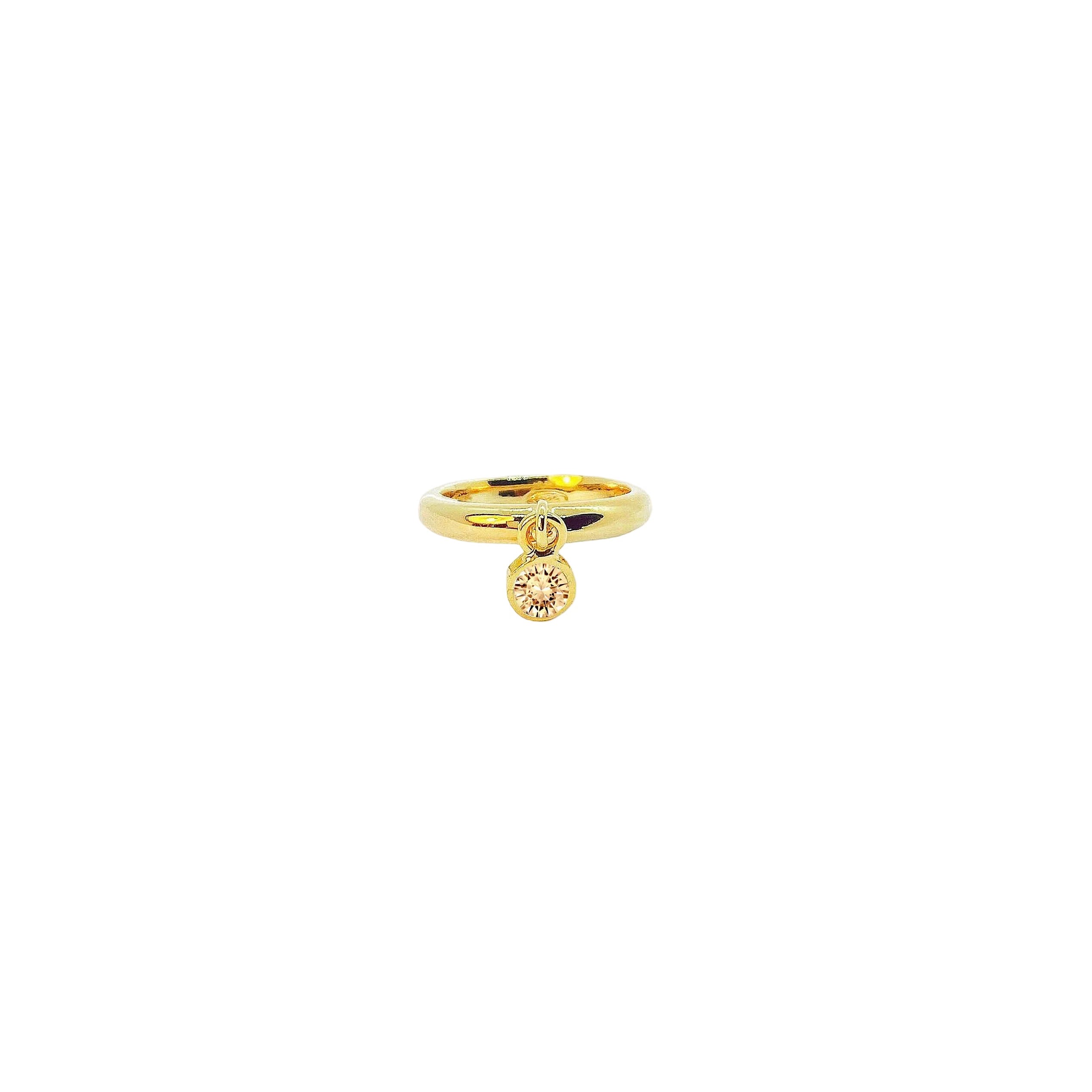Gold ring with a pink gemstone on a beige background