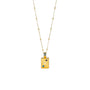 A gold-colored necklace with a rectangular pendant featuring a fish motif and blue and purple stones set within it.